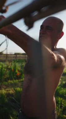 Orta yaşlı çiftçi şehir bahçesinin yakınına ahşap çardak kuruyor.