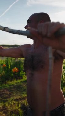 Kel çiftçi, şehir bahçesinde ahşap direklerle destek yapıları inşa ediyor.