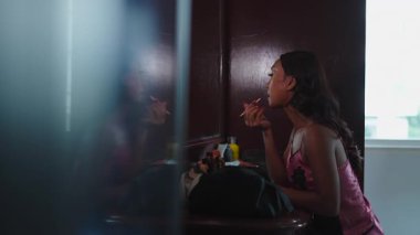 Genç trans kadın sabah aynaya bakarken ruj sürüyor - 4K Yatay