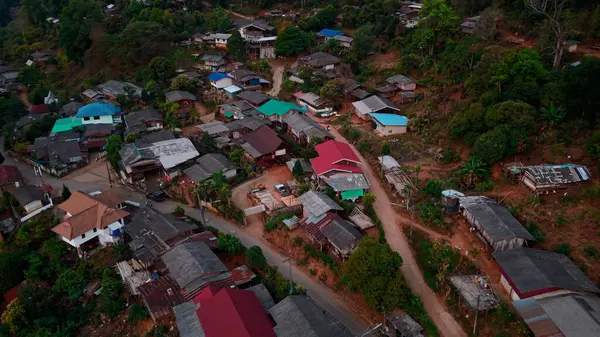 Renkli çatıları olan geleneksel evler yeşil bir dağ manzarasının ortasına kurulmuş huzurlu bir köyün manzarasını çiziyor.