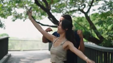 Genç çift gülümsüyor, ağaçların yanında birlikte anları yakalıyorlar.