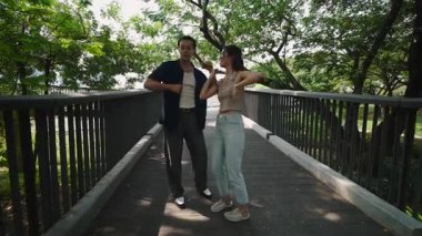 Neşeli partnerler neşeyle hareket ediyor, güneş ışığı parkı aydınlatırken yakın dans ediyorlar.