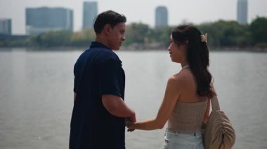 Romantik ortaklar el ele yürür, sakin göl kenarında manzaralı su ve manzara arka planında sohbet ederler.