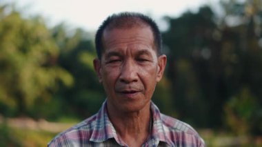 Asyalı çiftçi kameraya dalgın bir ifadeyle bakıyor kırsal yaşam tarzını somutlaştırıyor - 4K Yatay