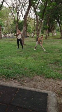 Yeşil ağaçların yanında uzanan, dışarıda egzersiz yaparken spor yapan çift.