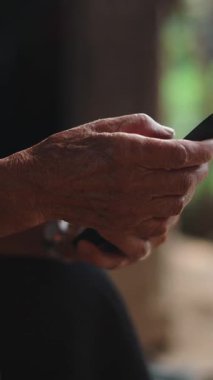 FullHD dikey akıllı telefon kullanan yaşlı bir Senatda kadınının elleri