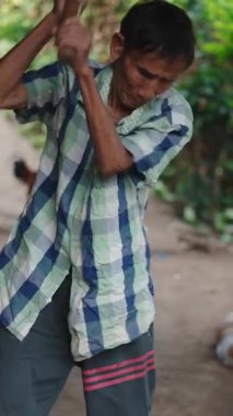 Lahu kabilesinden yaşlı bir çiftçi Tayland 'da ev yapımı baltayla odun kesiyor.