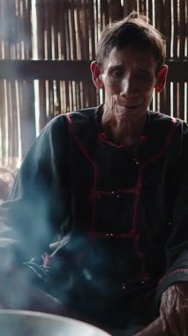 Duman yükseliyor, yaşlı bir lahu bağdaş kurup yangını seyrederken.