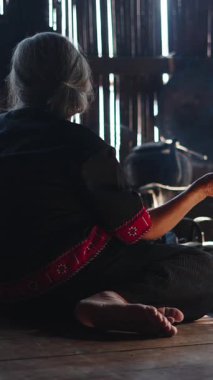 Yaşlı bir kadın geleneksel lahu mutfağı FullHD Dikey Mutfağı 'nda odun ateşinde yemek hazırlıyor.