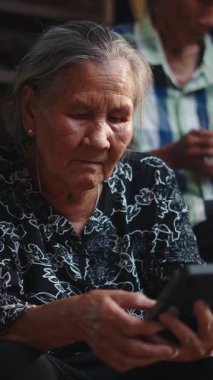 Üst düzey bir kadın arka planda FullHD dikey telefon kullanan bir adamla merdivenlerde oturuyor.