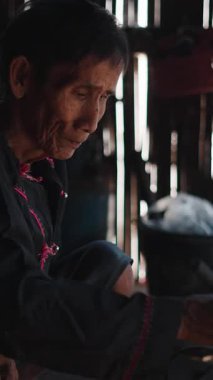 Yaşlı bir lahu kadını geleneksel yöntemleri kullanarak köy mutfağında yemek hazırlıyor.