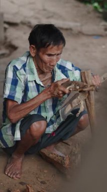 Asyalı Elder geleneksel ve eski usul FullHD dikey bir şekilde ağaçtan balta yapıyor.