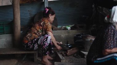 Yaşlı Vietnamlı bir kadın Vietnam 'daki mütevazı bir kulübede yemek hazırlamadan önce kömürü kesiyor - 4K Yatay