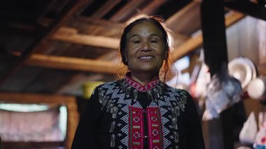 Geleneksel kıyafetler giymiş Taylandlı kadın, kırsal ve geleneksel Asya ahşap kulübesinde kameraya gülümsüyor - 4K Yatay