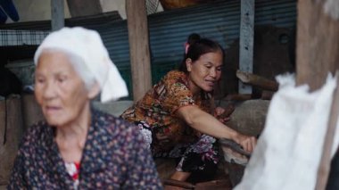 İki yaşlı Asyalı kadın mütevazı bir kulübede odun ateşinde yemek hazırlıyorlar - 4K Yatay