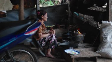 Taylandlı son sınıf öğrencisi çıplak ayakla bir kulübede geleneksel odun ateşinde çay hazırlıyor - 4K Yatay