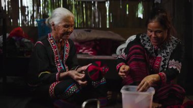 Geleneksel Asyalı kadınlar el yapımı tekstil işlerinde çalışıyorlar. Ahşap bir evde dikiş dikip sohbet ediyorlar. 4K Yatay.
