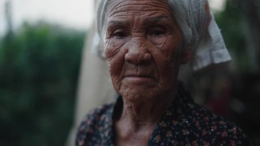 Yüzü buruşuk ve kafasında havlu olan sakin bir Asyalı kadının yakın plan portresi - 4K Yatay