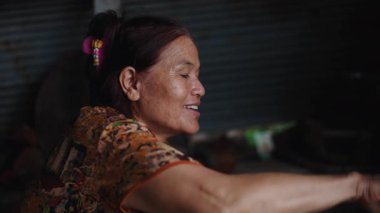 Mutlu ve gülümseyen bir Asyalı kadının portresi geleneksel yemekleri mütevazı bir kulübede hazırlıyor - 4K Yatay