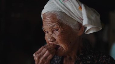 Az dişli yaşlı kadın, mütevazı bir çevrede zorlukla taze çilek çiğniyor - 4K Yatay