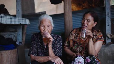 Yaşlı bir kadın ve kızı, basit ve kırsal bir atmosferde çay içerken bir anlık huzur paylaşıyorlar - 4K Yatay