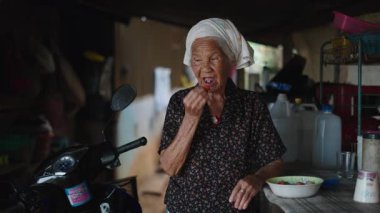 Yaşlı kadın evde oturmuş motosikletin yanında taze olgun çileklerin tadını çıkarıyor - 4K Yatay