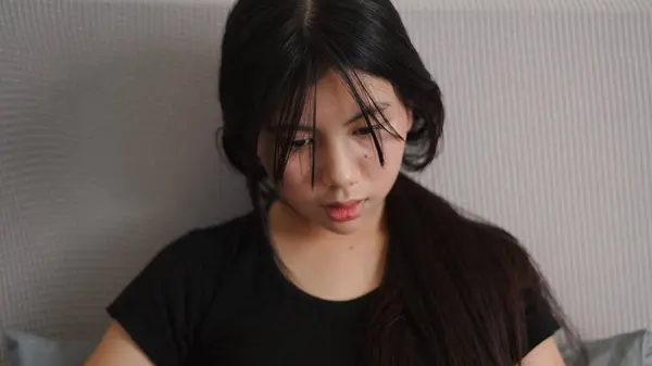 Asyalı kadın evde rahat bir kanepede dinlenirken kitap okumaktan zevk alıyor.