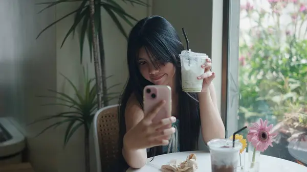 Müşteri içkisinin tadını çıkarıyor ve bir kafede selfie çekiyor.