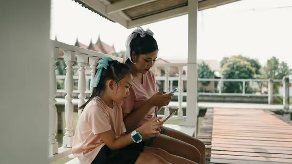 Genç kız, kadın verandanın korkuluklarında mesajlaşıyor.