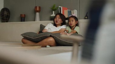 Anne ve kızı rahat bir vakit geçirip rahat oturma odalarında televizyon izliyorlar - 4K Yatay