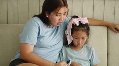 Asyalı bir anne kızına evde nasıl tablet kullanacağını öğretir - 4K Yatay