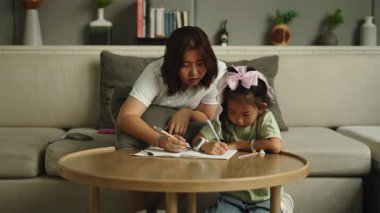 Annem küçük kızına oturma odasındaki kahve masasında oturarak yazmayı ve resim yapmayı öğretiyor. 4K Yatay
