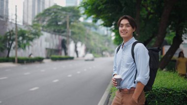 Profesyonel işadamı kahve içer, şehir caddesinde yürürken gülümser, iş kıyafeti giyer.