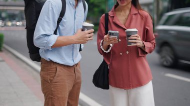 Profesyonel meslektaşlar şehir merkezinde kahve içerken akıllı telefonu inceliyor.