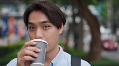 Genç profesyonel kahvesini yudumlarken sabah banliyö caddesinde yürürken