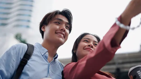 Gülümseyen iş adamları modern bir şehirde akıllı telefonlarıyla selfie çekiyorlar.