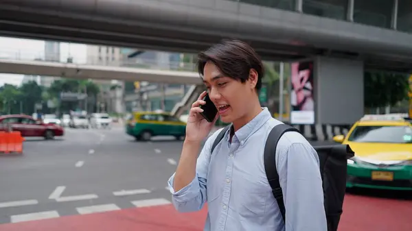 Genç Asyalı işadamı, işlek bir şehir caddesinde işe gidip gelirken bir telefon görüşmesi yapıyor.