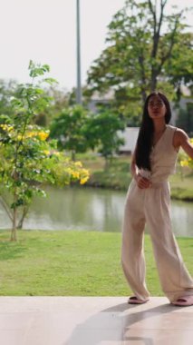 Genç bir Asyalı dansçı, göl kenarındaki FullHD Dikey Park 'ta koreografi yapıyor.
