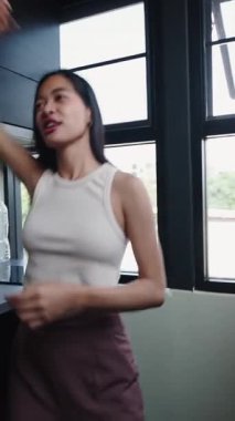 Genç Asyalı kadın modern mutfağında müzik dinlemekten hoşlanıyor.