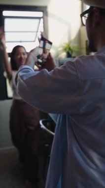 Genç Asyalı bir adam mutfakta dans ederken genç bir kızın fotoğraflarını çekiyor - FullHD dikey