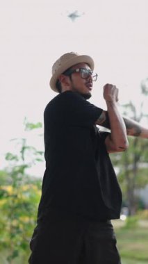 Sumro ve dövmeli genç Asyalı dansçı FullHD Dikey Park 'ta esneme hareketleri yapıyor.