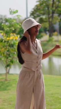 Genç Asyalı kadın şehir parkında kol ve bacak esneme hareketleri yapıyor.