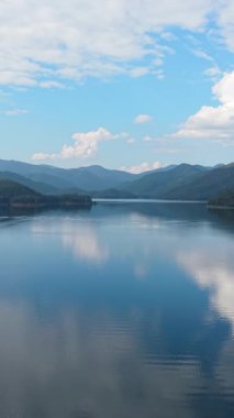 Su yüzeyine yansıyan dağ sırası, göle yansıyan bulutlar, FullHD dikey