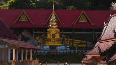 Süslü ne pong yaeng nok Budist tapınağı canlı kırmızı çatı, pırıl pırıl altın chedi, yaslanan Buda heykeli
