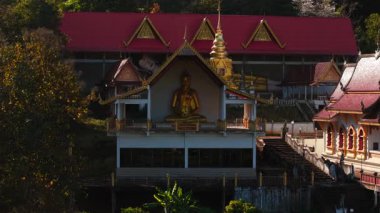 Altın Buda heykeli, süslü Wat Pong Yeng Nok tapınağında huzur içinde meditasyon yapıyor. Geleneksel Thai ayininin ruhani huzurunu vurguluyor.