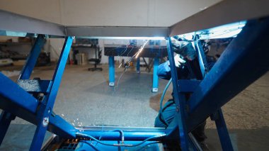 Profesyonel kaynakçı, endüstriyel üretim tesisinde MIG kaynak tekniğini kullanarak metal bileşenlerini birleştiriyor.