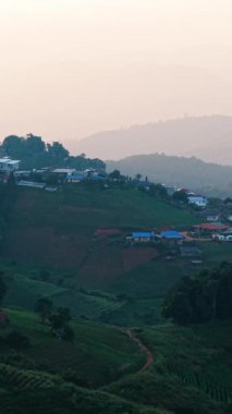 Gün batımında yeşil bir dağ yamacında çadır ve kubbeler - FullHD Dikey