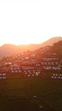 Güneş ışığı, gün batımında bir dağ köyünü çadırlarla aydınlatır.