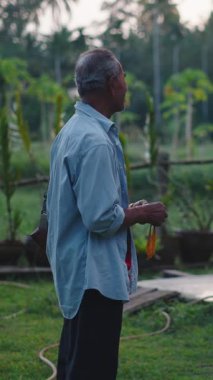 Tayland 'da bir evin önündeki tropikal bir bahçede dikilen iki Asyalı sohbet ediyorlar.