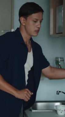 Ev Mutfağında dikey ayakta duran Adam Şişeden Elektrik İbriği 'ne Sıcak Su Döküyor